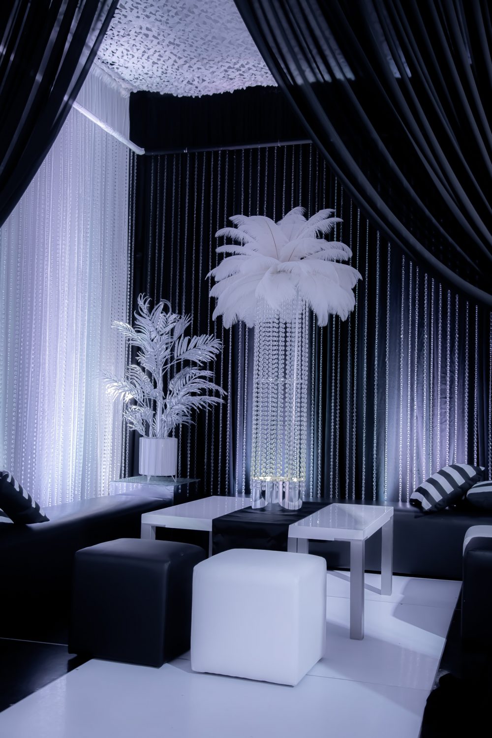 black and white themed event lounge area with ottomans and centrepieces
