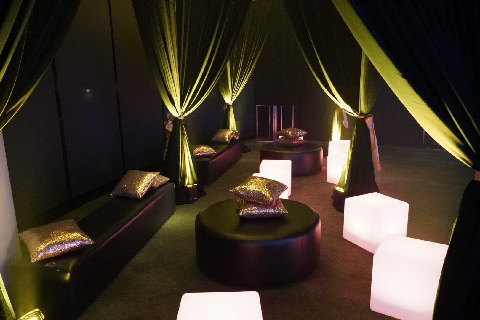 studio 54 themed event lounge area with ottomans draping and illuminated seats