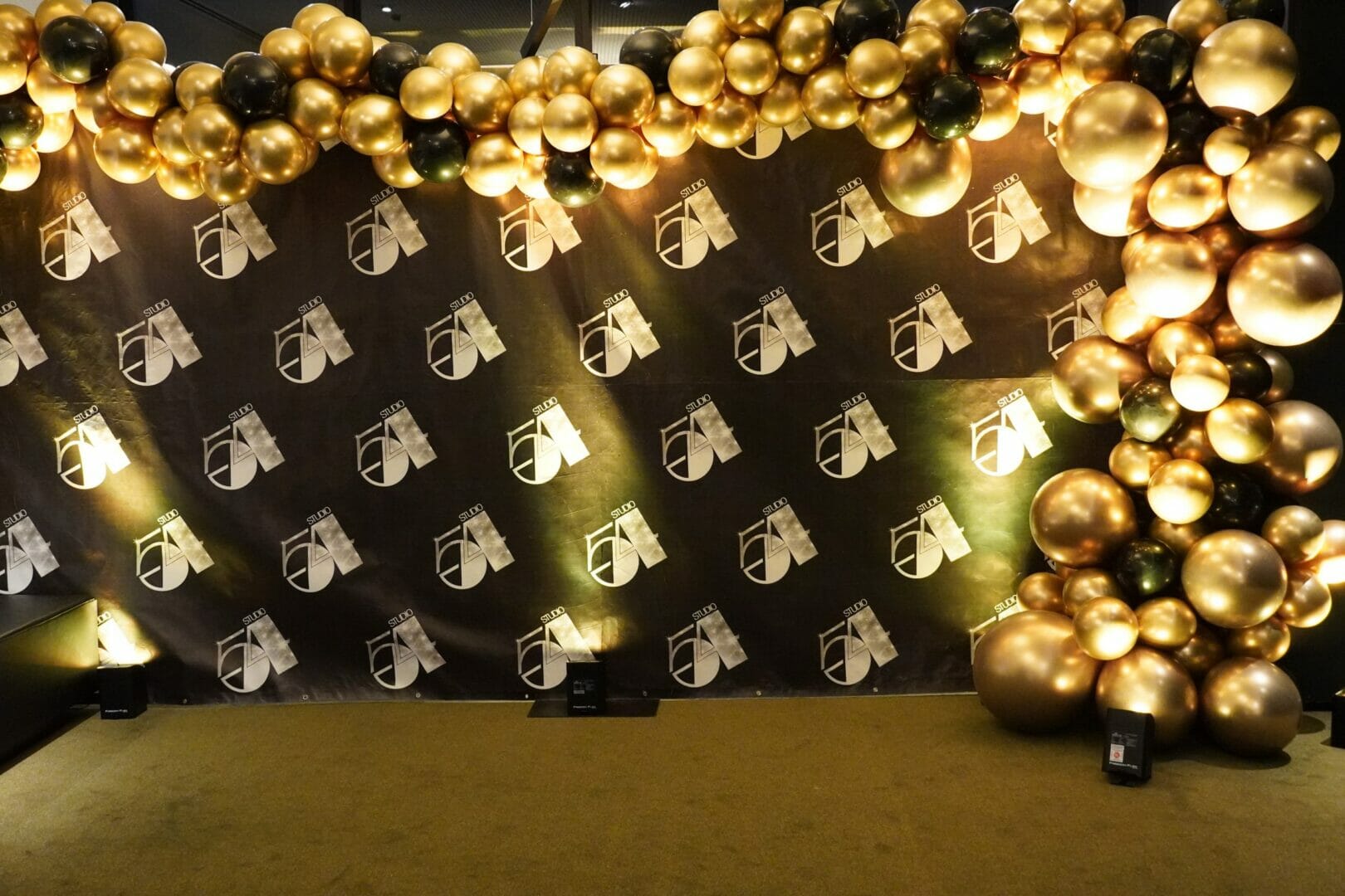 Studio 54 themed backdrop and black and gold balloon garland