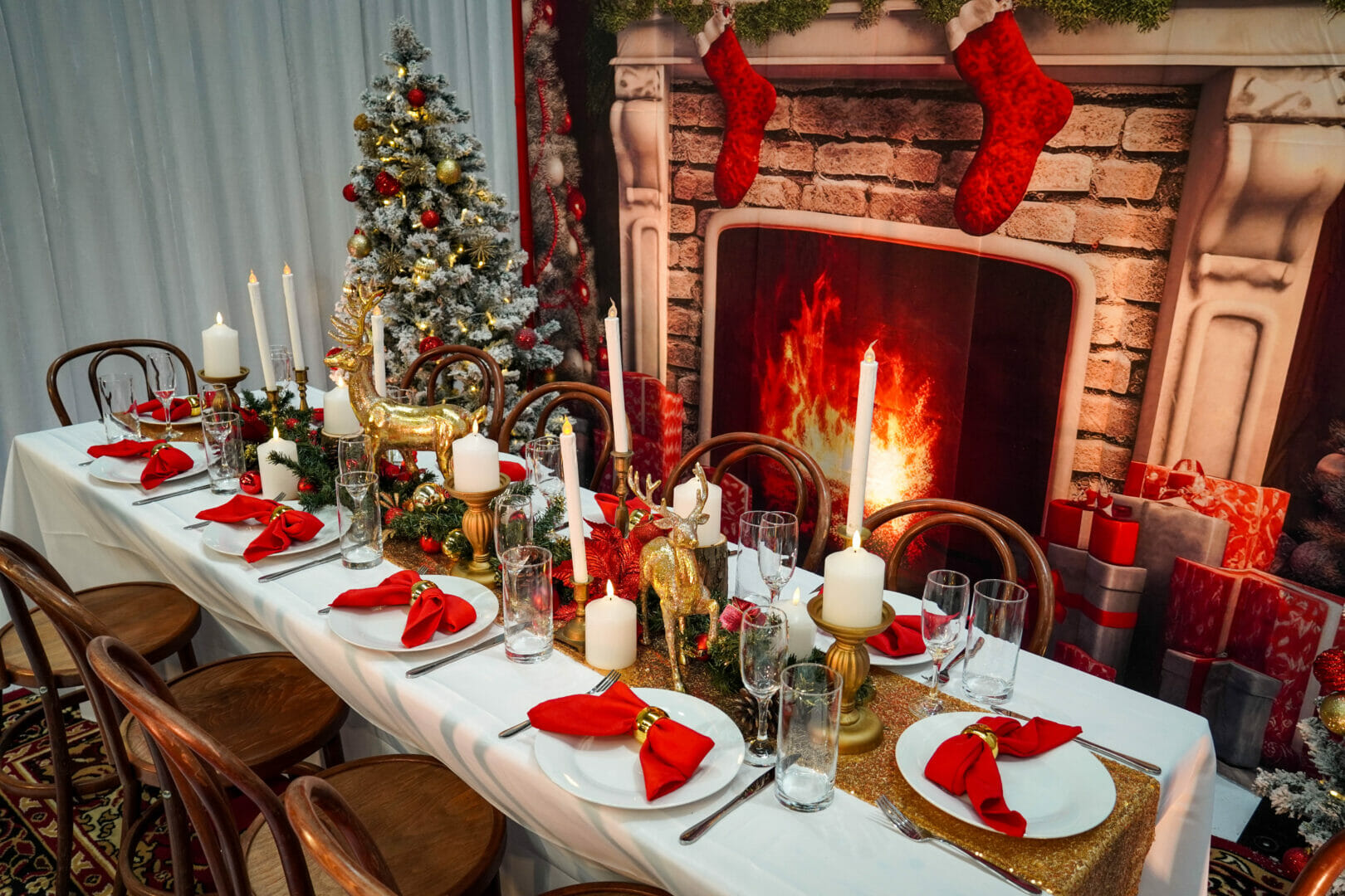 christmas themed dinner table setup with ornaments, napkins, garlands, candles, and themed backdrop