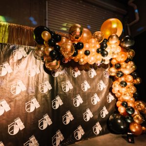 studio 54 themed backdrop with black and gold balloon garland