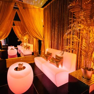 illuminated lounge furniture and gold draping at a studio 54 themed party