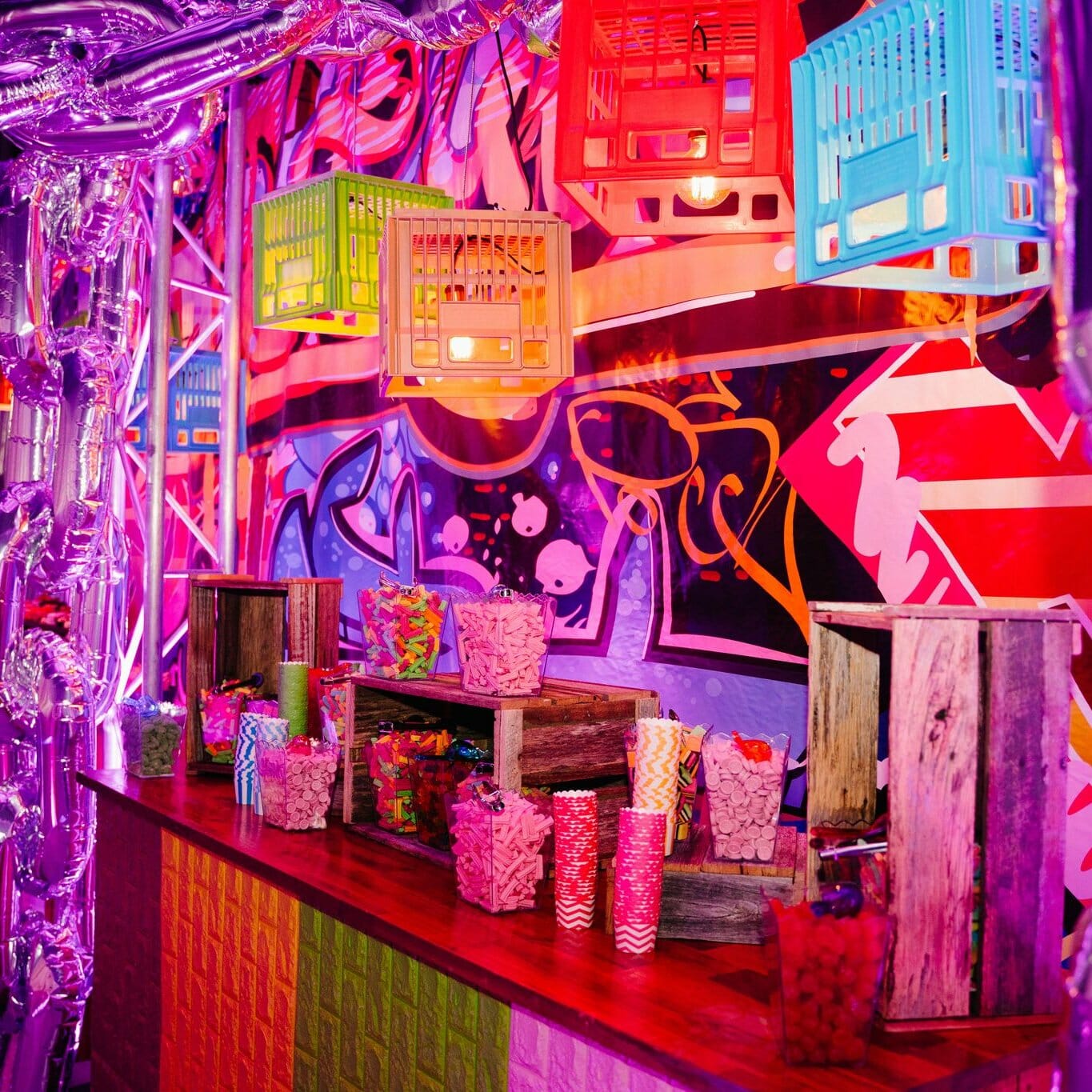 Graffiti themed party setup candy buffet, crates, pendant lights, themed backdrop