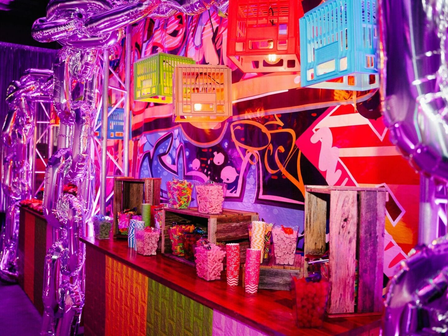 Graffiti themed party setup candy buffet, crates, pendant lights, themed backdrop