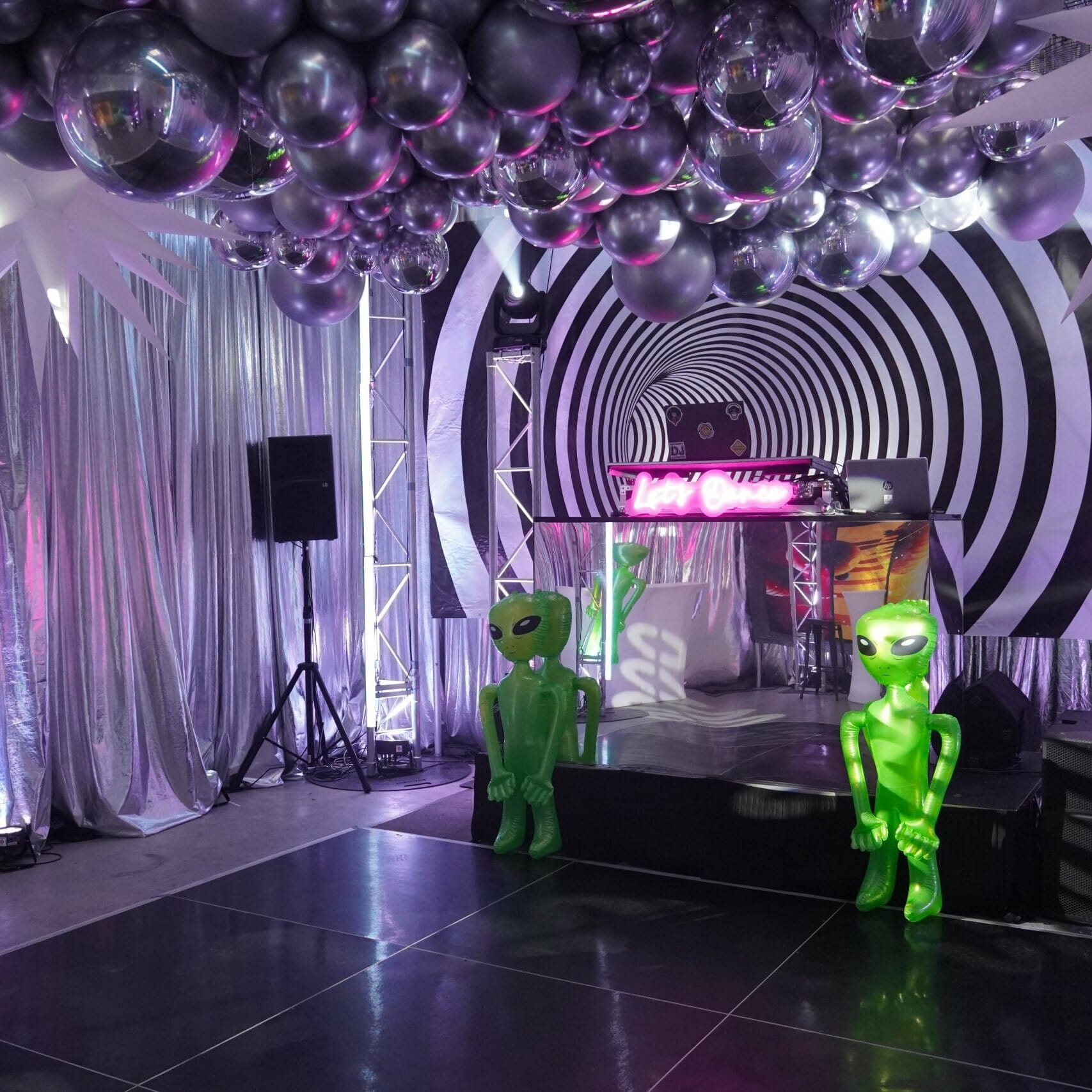 Dance floor area of space themed party. Party lights, inflatable props, balloons, themed backdrops.