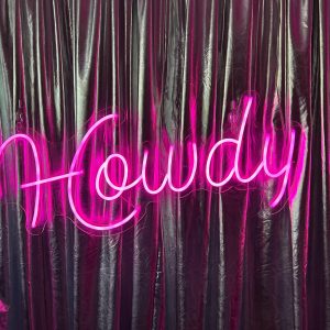 Pink neon howdy sign and silver drape