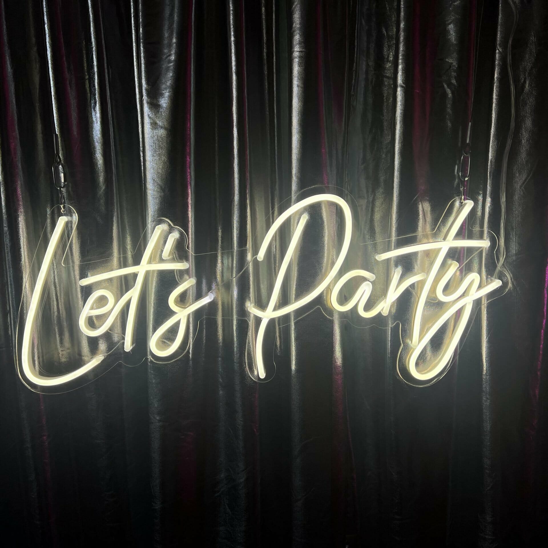 lets party neon sign with silver draping