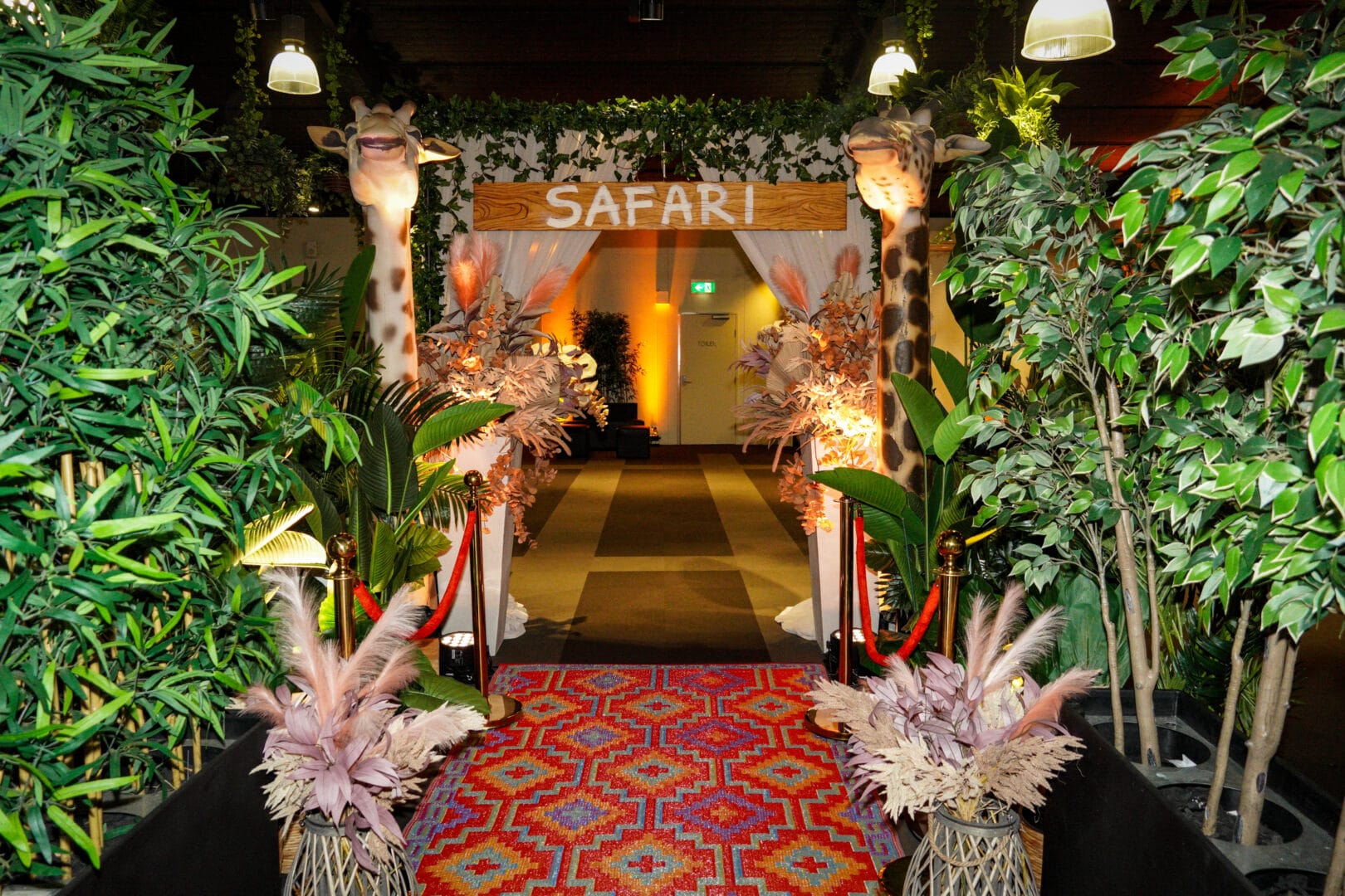 Safari themed entranceway featuring greenery, Giraffe props, dried florals, rug