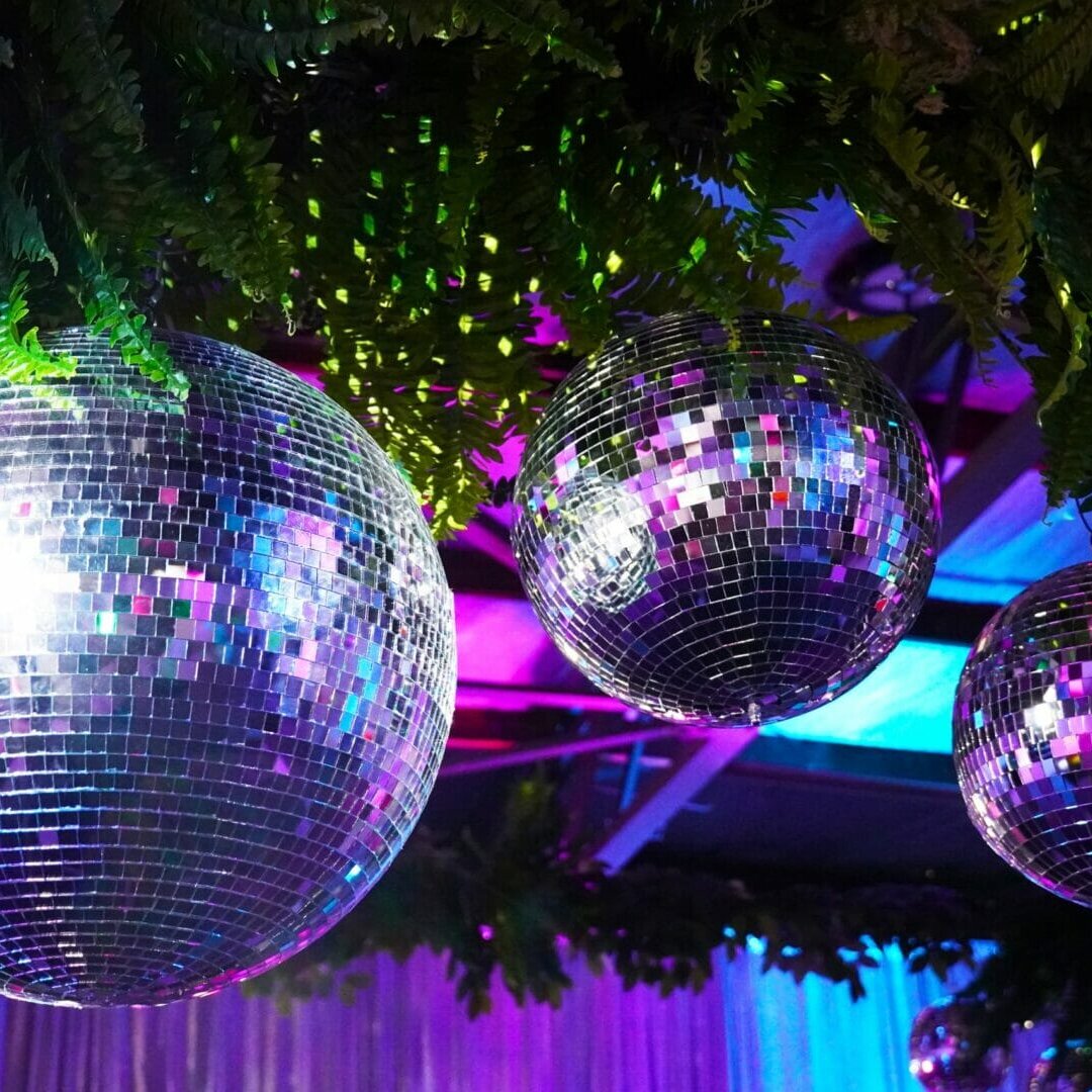 silver mirror balls and greenery at neon disco party theme