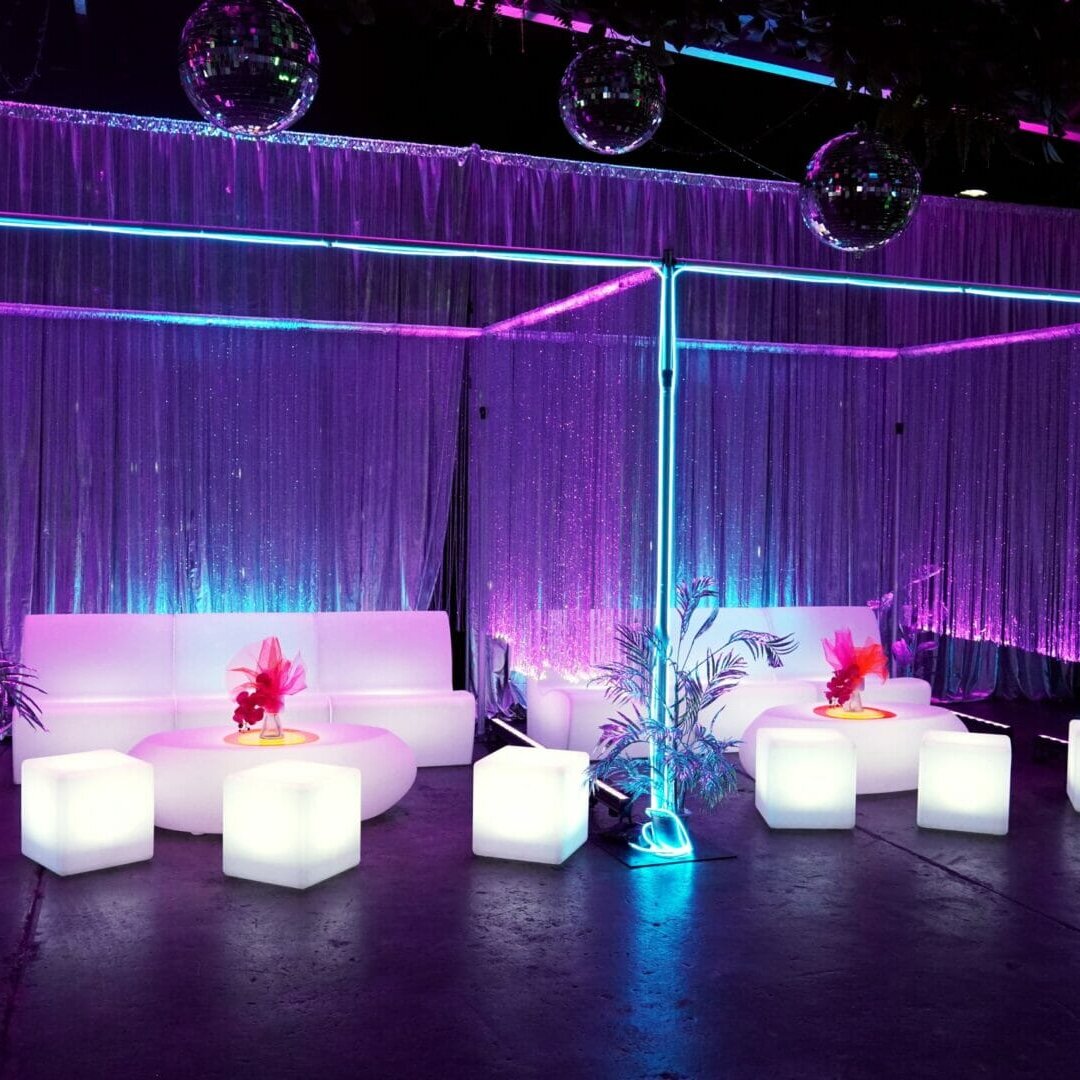 illuminated sofas, cubes, and coffee tables with beaded curtains, silver drape, neon lights and mirror balls