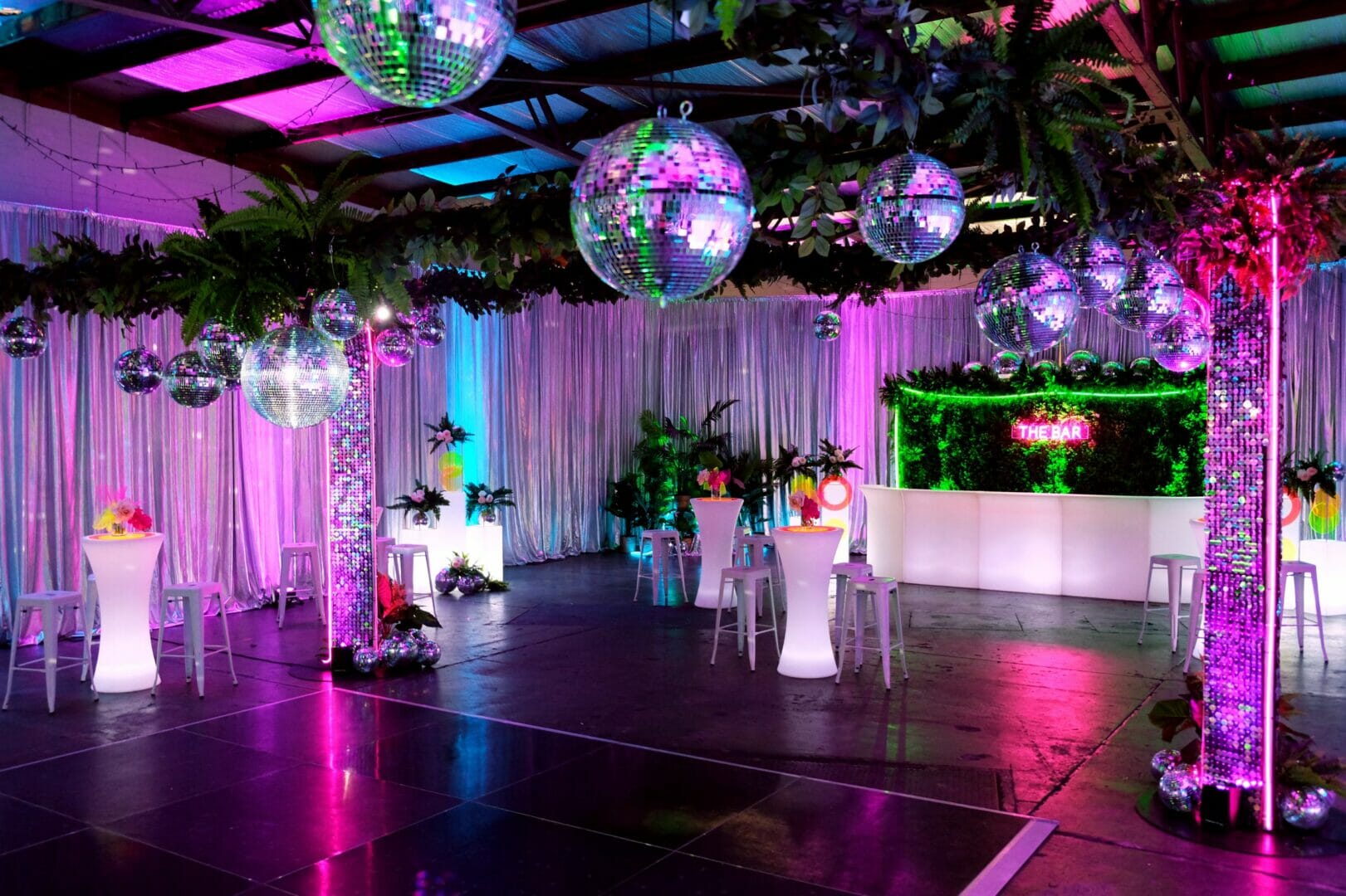 mirror balls, greenery, dance floor, neon lights, sequin panels at neon disco party theme