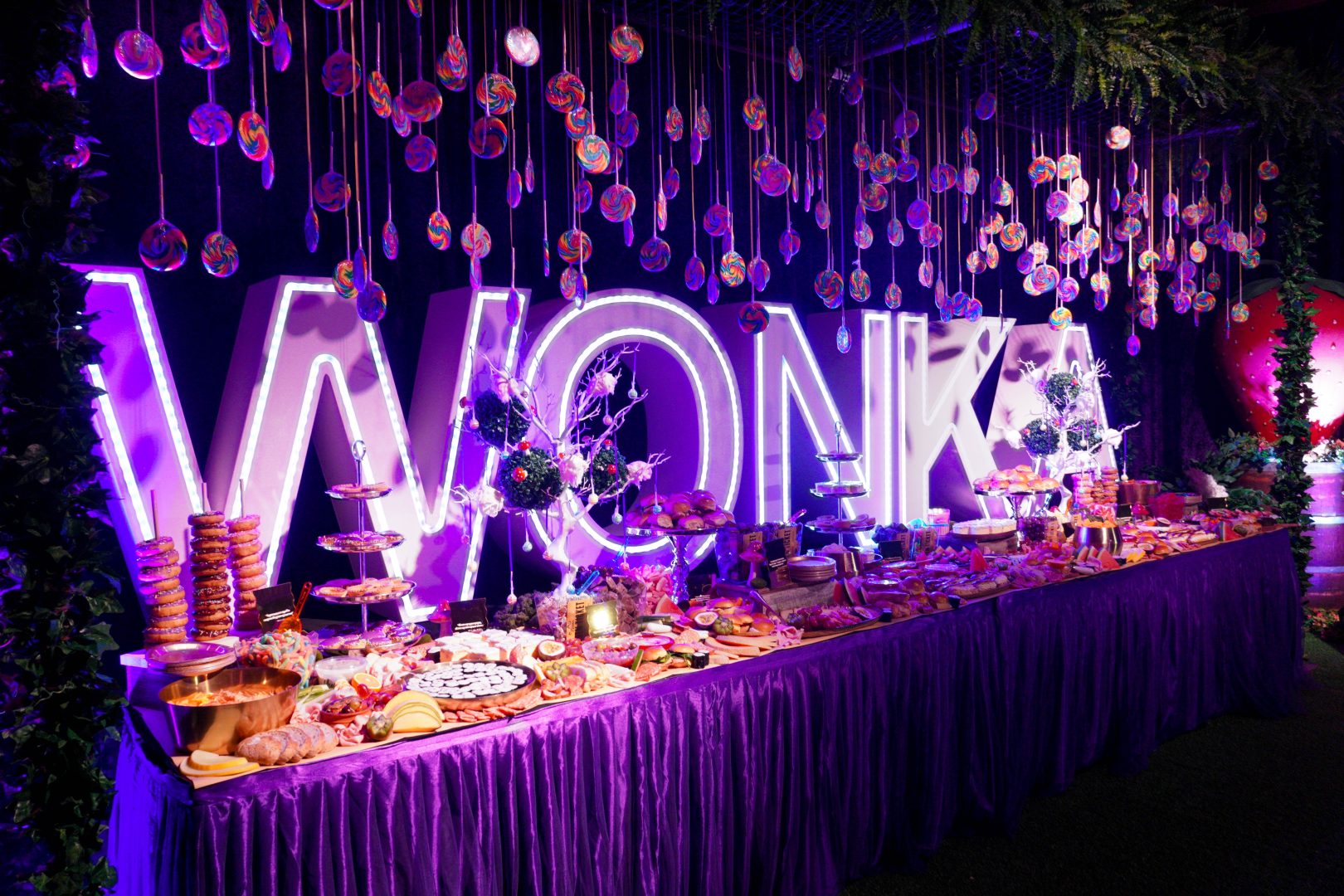 Grazing table at a candyland party with canapes, candy, pastries, and lollipops