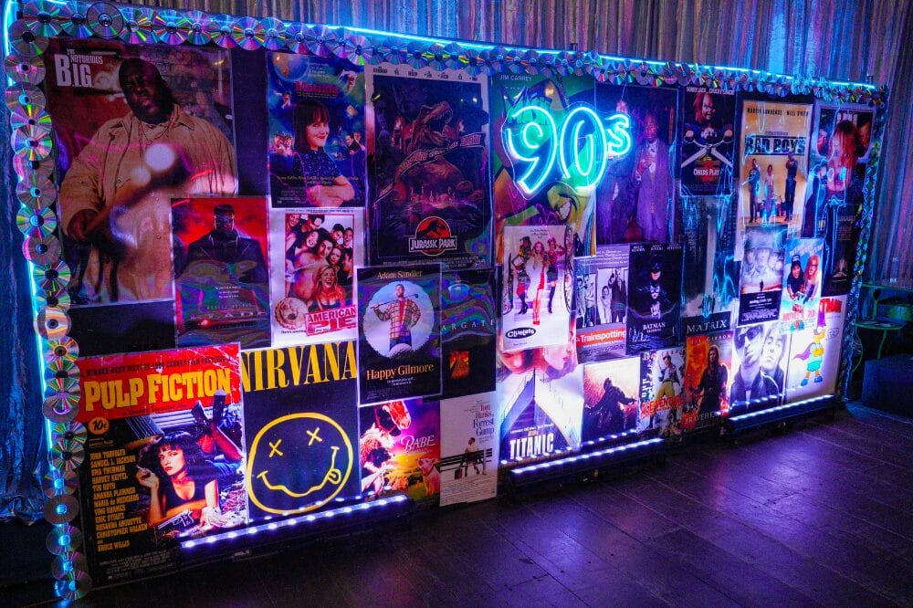 90s neon sign sitting on a backdrop of 90s movie posters