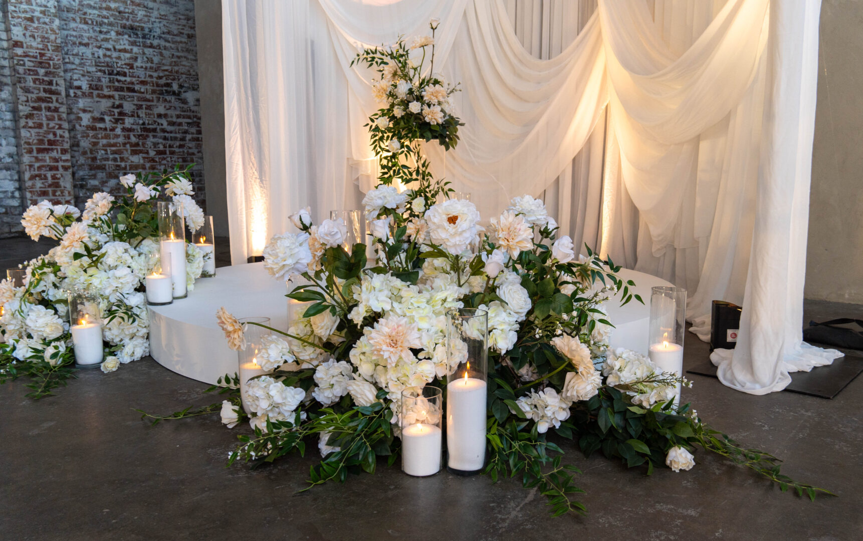 white florals and lush greenery with candles for a wedding ceremony setup