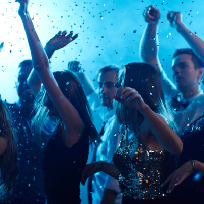 Ecstatic friends dancing in confetti in night club